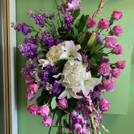 Standing floral spray with pink roses, white lilies, and purple blooms