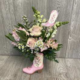 Pink roses and lilies arranged in a decorative boot vase