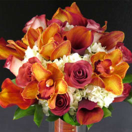 Bouquet of orange orchids, burgundy roses, and white hydrangeas in a vase