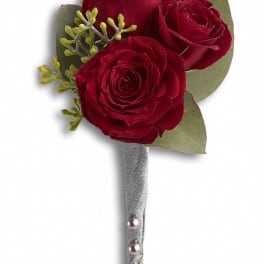 Three red rose blooms arranged as a boutonniere with silver ribbon and pearl pins