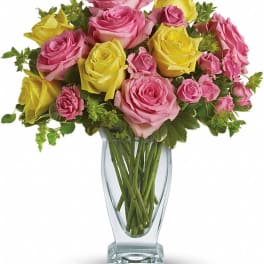 Pink and yellow roses arranged in a clear glass vase