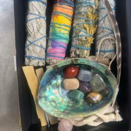 Box of bundled sage sticks, crystals, and an abalone shell