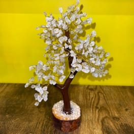 Decorative crystal tree on a wooden base against a yellow background