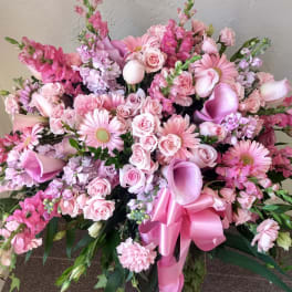 Large pink floral spray with roses, gerbera daisies, calla lilies, and a ribbon bow