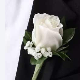 White rose boutonniere with small white filler flowers on a black tuxedo lapel