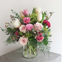 Bouquet of pink roses, white tulips, and carnations in a glass vase