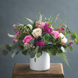 Pink and cream roses in a white vase with mixed greenery