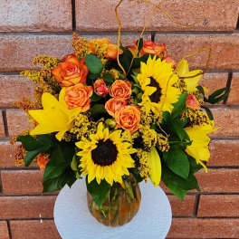 Bouquet of yellow sunflowers and orange roses in a glass vase