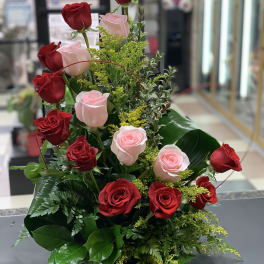 Tall arrangement of red and pale pink roses with greenery