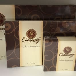 Three boxes of Coblentz Deluxe Assortment chocolates stacked together