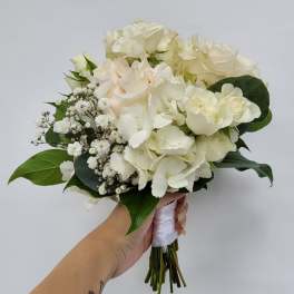 Handheld bouquet of white roses and hydrangeas with baby's breath