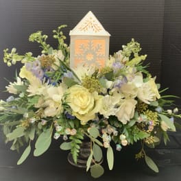 Cream and pale yellow floral arrangement with a lit lantern centerpiece