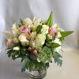 Pink and white roses with lilies in a glass vase