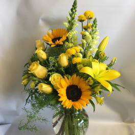 Yellow bouquet with sunflowers and roses in a glass vase