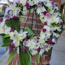 Large floral wreath with white, lavender, and pink flowers on a stand