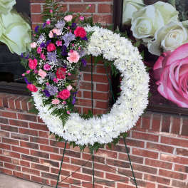 Heart-shaped floral wreath on a stand with white and mixed pink-purple flowers
