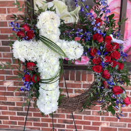 Two floral wreaths on stands, one white cross and one red rose heart