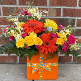 Bright mixed bouquet in an orange gift box with a polka-dot ribbon