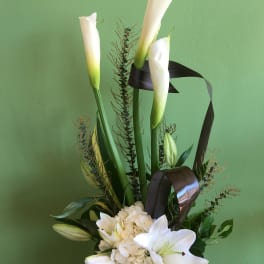 White calla lilies and lilies arranged with hydrangea in a vase