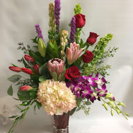Mixed bouquet with roses, lilies, hydrangea, and orchids in a glass vase
