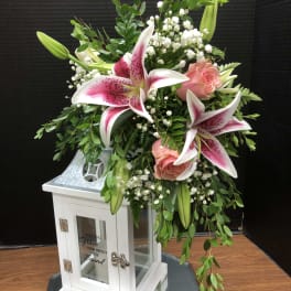 Pink lilies and roses arranged in a white lantern vase