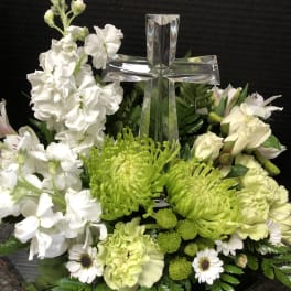 White and green floral arrangement with a clear glass cross centerpiece
