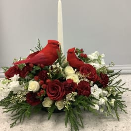 Red cardinal figurines in a floral centerpiece with a tall white candle