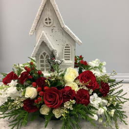 Red and white floral arrangement around a small white church decoration