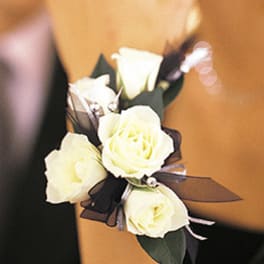 White rose corsage with dark ribbon on a wrist