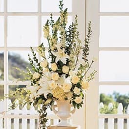 Tall white floral arrangement in a pedestal vase