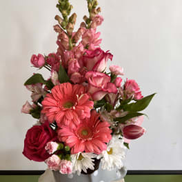 Pink and white mixed flower arrangement in a gray polka-dot vase