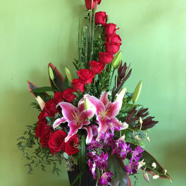 Tall arrangement of red roses and pink lilies in a black vase
