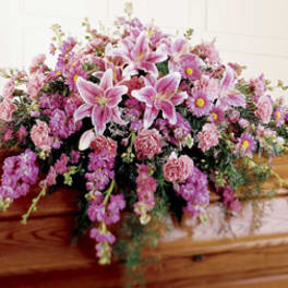 Pink and purple floral spray on a wooden casket