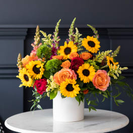 Bright mixed bouquet in a white vase with sunflowers and roses
