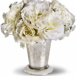 White roses in a silver vase with delicate filler flowers