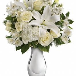White lilies and roses arranged in a clear glass vase