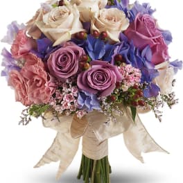 Bouquet of cream, pink, and purple roses with a ribbon wrap