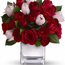 Red and pale pink roses arranged in a clear glass vase