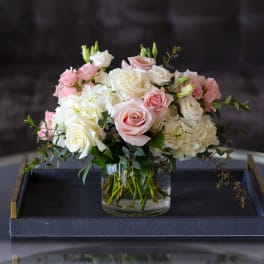 Pink and white roses arranged in a glass vase