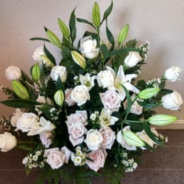 White roses and lilies arranged with greenery in a low bouquet
