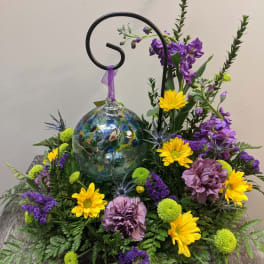 Purple and yellow floral arrangement with a glass ornament centerpiece