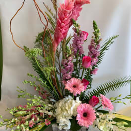 Tall pink floral arrangement in a rectangular vase with gerberas and orchids