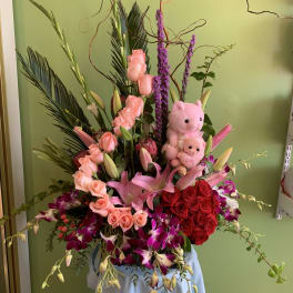 Large pink and red floral arrangement with two teddy bears