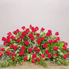 Large arrangement of red roses with trailing greenery on a table