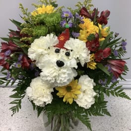 Colorful bouquet with a dog face made of white carnations in a glass vase