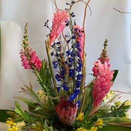 Tall tropical arrangement with pink and blue flowers in a vase