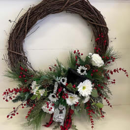 Holiday wreath with white flowers, red berries, and a plaid ribbon