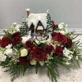 Winter floral arrangement with a snowy cottage centerpiece and red and white roses