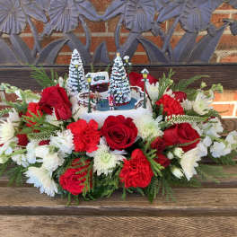 Red and white floral arrangement with a winter village centerpiece