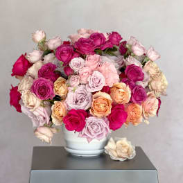 Bouquet of pink, peach, and cream roses in a white vase